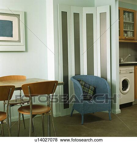 Stock Photo - Blue tub chair and folding screen in modern studio apartment with dining table. Fotosearch