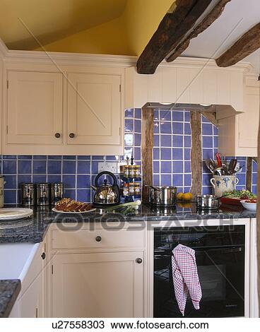 Blue Wall Tiles And Cream Fitted Cupboards In Cottage Kitchen