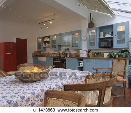 Stock Image - Blue+white cloth on table in kitchen dining room extension with turquoise fitted units. Fotosearch