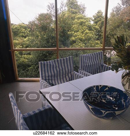 Blue+white striped loosecovers on chairs in modern dining room with large window View Large Photo Image Stock Image - Blue+white striped loosecovers on chairs in modern dining room with large window. Fotosearch