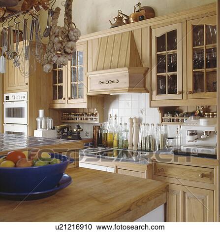 Bowl of fruit on wooden worktop in fitted wooden kitchen with row of glass bottles on oil above hob View Large Photo Image Stock Image - Bowl of fruit on wooden worktop in fitted wooden kitchen with row of glass bottles on oil above hob. Fotosearch