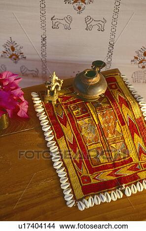 Picture - Brass pot on traditional Rajastani embroidered cloth and pink rhododendrons in vase on wooden table in tent. Fotosearch