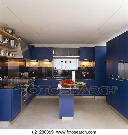 Stock Photo - Bright blue fitted units in modern white kitchen. Fotosearch