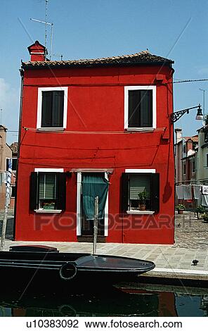 Stock Image - Bright red house beside canal in Venic&#10;. Fotosearch