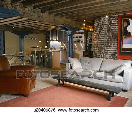 Stock Photograph - Brown leather armchair and white sofa in openplan loft conversion living room. Fotosearch