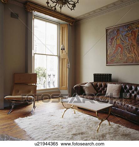 Brown Leather Chesterfield Sofa And Metal Framed Coffee Table In Living Room With Tall Windows And Flokati Rug Stock Photography U21944365 Fotosearch