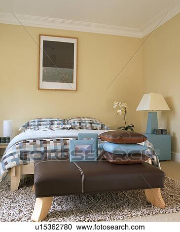 Stock Image - Brown upholstered stool in neutral bedroom. Fotosearch