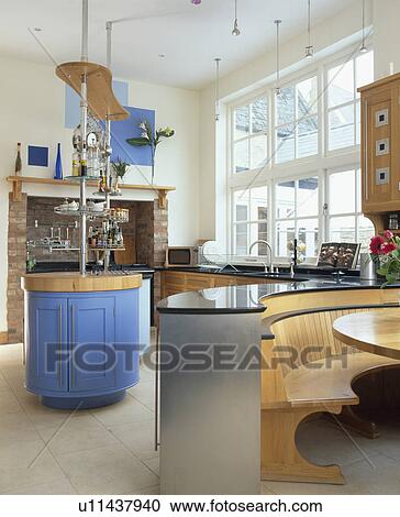 Stock Image - Built-in seating in dining area in large modern kitchen with blue island unit. Fotosearch