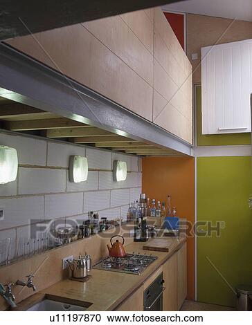 Bulkhead lighting on white tiled wall above worktop with hob in modern kitchen with green door View Large Photo Image Stock Image - Bulkhead lighting on white tiled wall above worktop with hob in modern kitchen with green door. Fotosearch