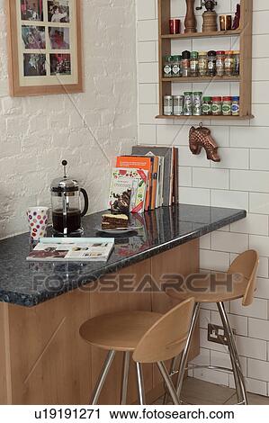 Stock Image - Cafetiere on granite-topped breakfast bar with plywood stools. Fotosearch