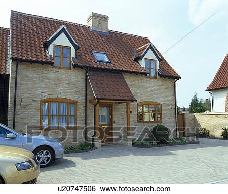 Stock Photograph - Cars parked on paved drive in front of newly-built house on small village estate. Fotosearch