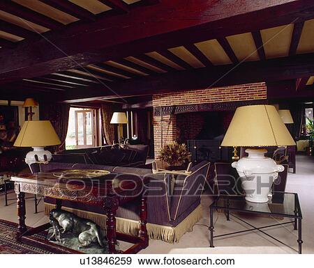 Carved Wooden Table Behind Brown Knole Sofa And Cream Lamps In