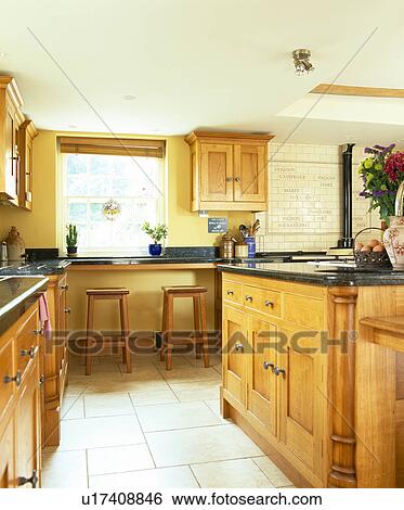 Stock Photograph - Ceramic tiled floor in country kitchen with fitted wooden units. Fotosearch