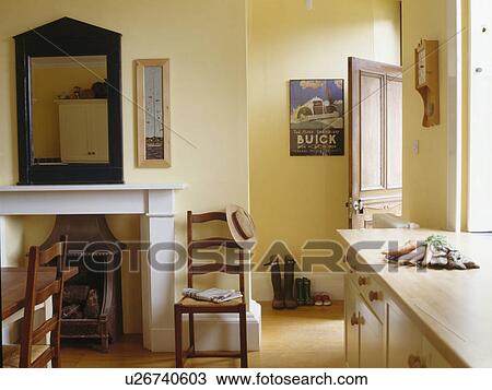 Stock Image - Chair beside fireplace in small traditional cream kitchen dining room. Fotosearch