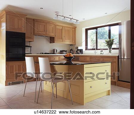 Chairs at breakfast bar on island unit in modern kitfchen with fitted wood units View Large Photo Image Stock Image - Chairs at breakfast bar on island unit in modern kitfchen with fitted wood units. Fotosearch