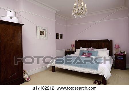 Chandelier above bed with white bed-linen and turquoise throw in pastel pink bedroom View Large Photo Image Stock Image - Chandelier above bed with white bed-linen and turquoise throw in pastel pink bedroom. Fotosearch