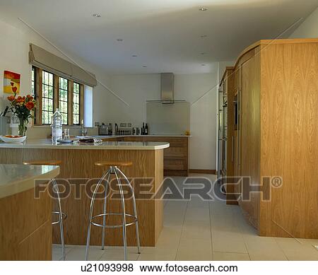 Stock Photo - Chrome stools at peninsular breakfast bar in modern kitchen with ceramic tiled floor. Fotosearch