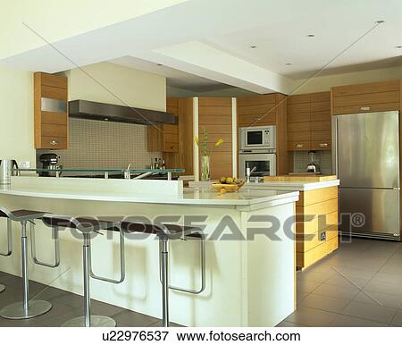 Chrome stools at white breakfast bar in modern kitchen View Large Photo Image Stock Photo - Chrome stools at white breakfast bar in modern kitchen. Fotosearch