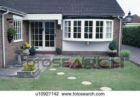 Stock Image - Circular paving stones across lawn to front door of bungalow with bow window. Fotosearch