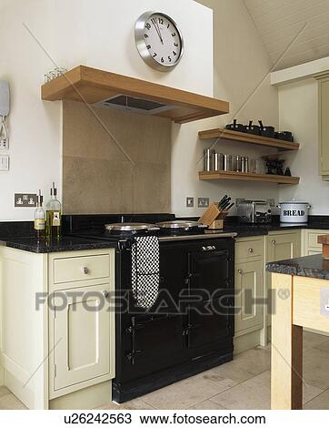 Circular stainless steel clock above black Aga oven in modern country kitchen View Large Photo Image Stock Image - Circular stainless steel clock above black Aga oven in modern country kitchen. Fotosearch