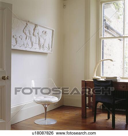 Stock Photograph - Classical plasterwork frieze on wall in small study with perspex Tulip chair and traditional desk. Fotosearch