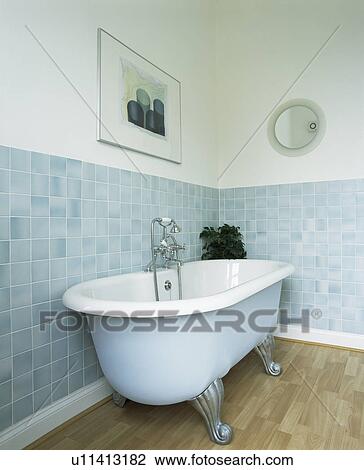 Stock Image - Clawfoot bath in bathroom with pastel blue wall tiles. Fotosearch