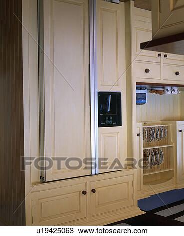 Stock Image - Close-up of American-style refrigerator in pale wood fitted kitchen unit. Fotosearch