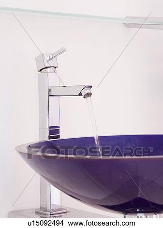 Close-up of angular chrome tap pouring water into circular black glass basin View Large Photo Image Picture - Close-up of angular chrome tap pouring water into circular black glass basin. Fotosearch