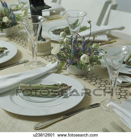 Stock Image - Close-up of asparagus on white plates on table set for lunch. Fotosearch