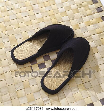 Stock Photograph - Close-up of black slippers on rush mat. Fotosearch