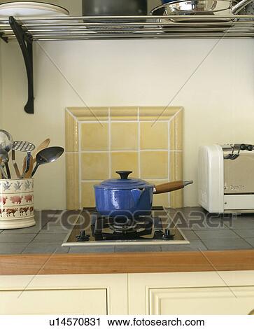 Stock Image - Close-up of blue saucepan on halogen hob. Fotosearch