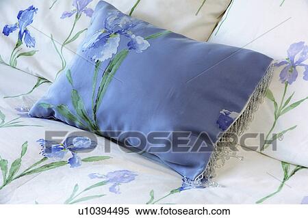 Stock Photography - Close-up of blue silk cushion on bed with blue iris-motif bedlinen. Fotosearch
