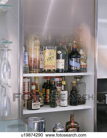 Stock Image - Close-up of bottles of liquers and spirits on shelves in kitchen cupboard. Fotosearch