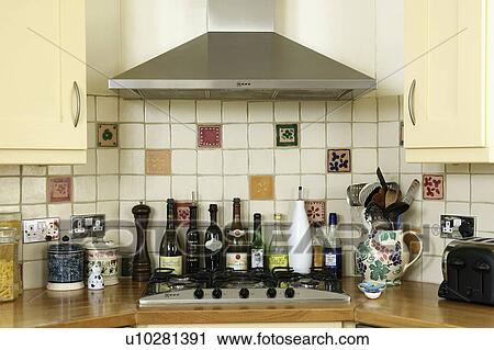 Stock Image - Close-up of bottles of wine and oil below stainless steel extractor. Fotosearch