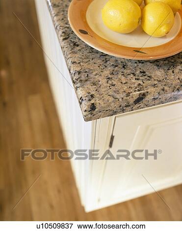 Stock Photo - Close-up of bowl of lemons on kitchen unit with granite worktop. Fotosearch