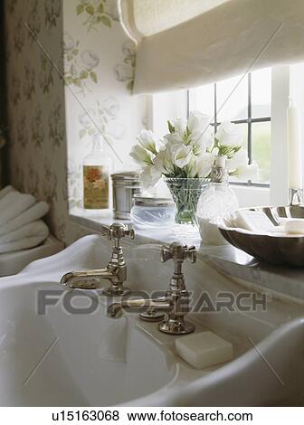 Stock Photo - close-up of brass taps on porcelain basin below window. Fotosearch