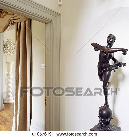 Stock Image - Close-up of bronze classical statue beside doorway. Fotosearch