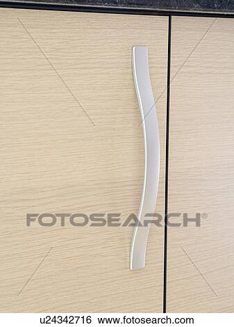 Stock Photograph - Close-up of brushed-steel handle on kitchen cupboard. Fotosearch
