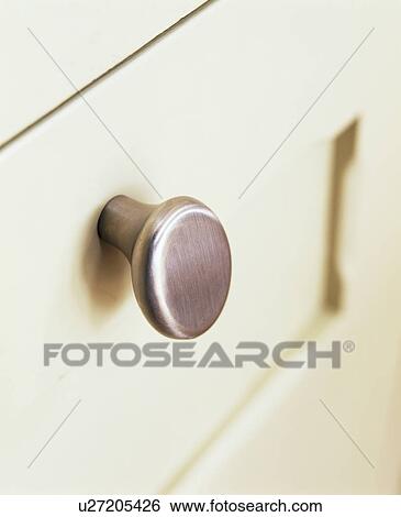 Stock Photograph - Close-up of brushed steel handle on cream drawers. Fotosearch