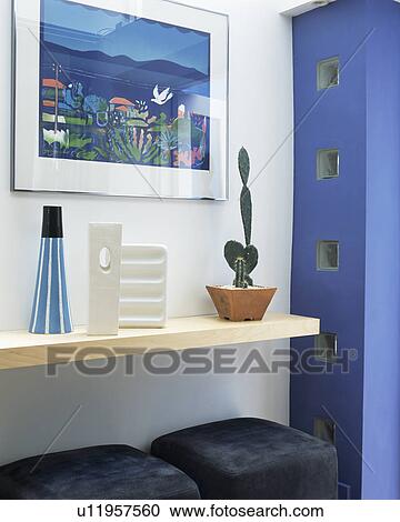 Stock Image - Close-up of cactus and vases on shelf below modern picture. Fotosearch