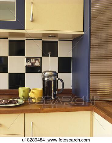 Picture - Close-up of cafetiere on worktop below black+white wall tiled splashback. Fotosearch