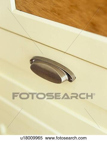 Stock Photography - Close-up of chrome handle on cream drawer. Fotosearch