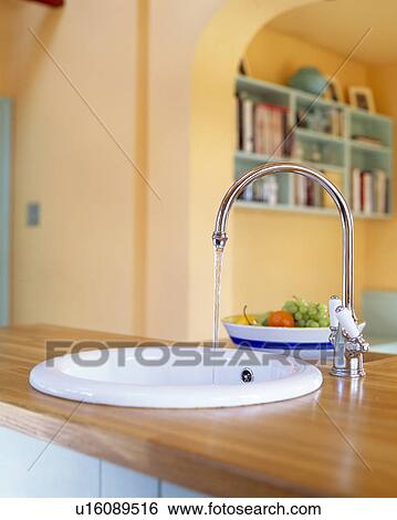 Close-up of chrome mixer tap pouring water into white circular sink in island unit View Large Photo Image Stock Photograph - Close-up of chrome mixer tap pouring water into white circular sink in island unit. Fotosearch