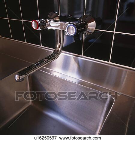 Stock Photo - Close-up of chrome tap and stainless steel sink. Fotosearch