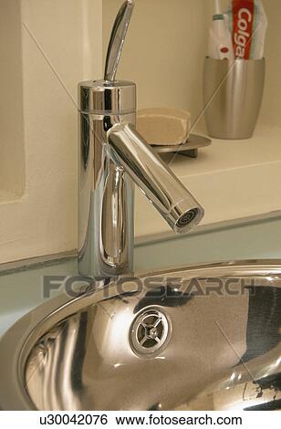 Stock Photograph - Close-up of chrome tap and stainless steel basin. Fotosearch