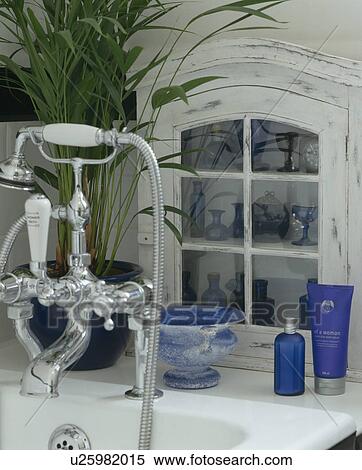 Stock Photography - Close-up of chrome taps and shower head and small white cupboard. Fotosearch