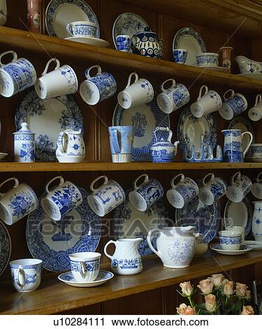 Stock Image - Close-up of collection of blue+white cups and jugs on kitchen shelves. Fotosearch