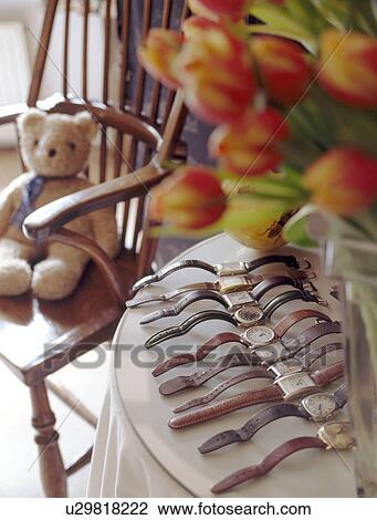 Stock Image - Close-up of collection of old watches beside chair with teddybear. Fotosearch
