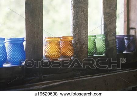 Stock Photo - Close-up of colourful glass candle holders on window sill. Fotosearch