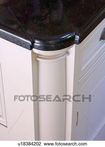 Stock Image - Close-up of corner of white kitchen unit with black worktop. Fotosearch